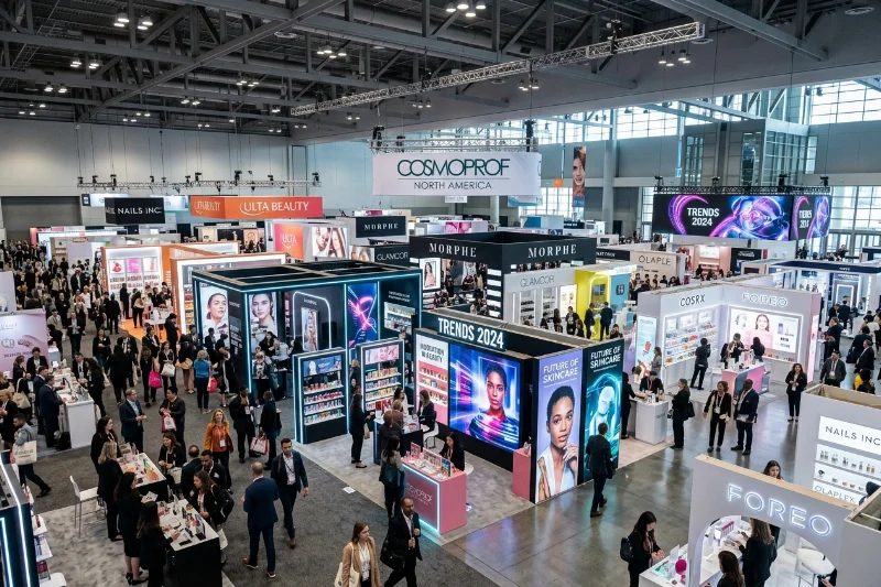 Professional trade show floor at Cosmoprof North America showing cosmetics booths and industry experts.